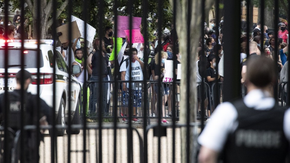 Säkerhetsvakter står utanför Vita huset i Washington på fredagen medan demonstranter protesterar utanför grindarna.