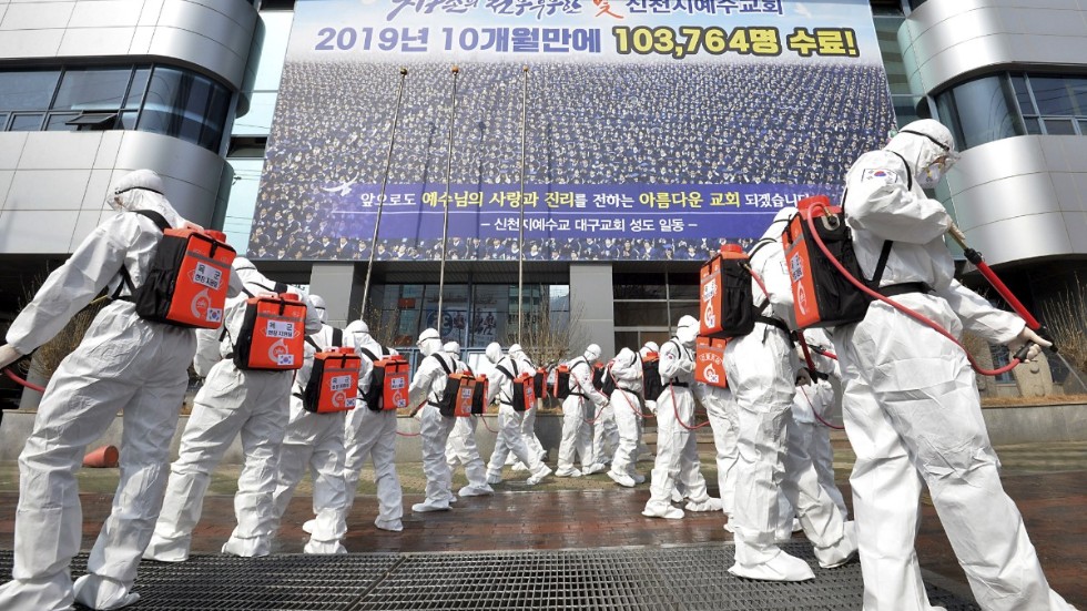 Soldater klädda i skyddsutrustning sprejar disinfektionsmedel för att förhindra smittspridning utanför Shincheonjikyrkan i Daegu. Arkivbild.