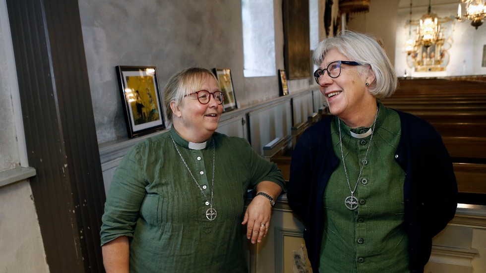 Lena Jansson (till vänster) och Karin Hagvil (till höger) är båda diakoner i Motala församling. Bakom den syns en del av Kent Wistis utställning i Motala kyrka.
