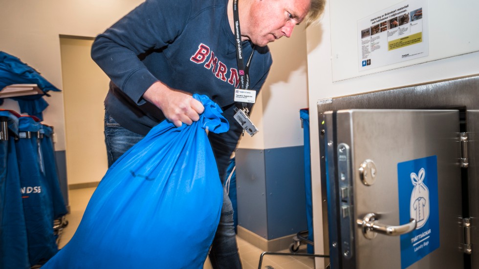 Tommie Sagström, controller på fastighetavdelningen visar hur sugsystemet i nya 100-huset för tvätt och sopor fungerar. Här slänger han in en säck med tvätt i en lucka i väggen där det hamnar i ett underjordiskt rörsystem.