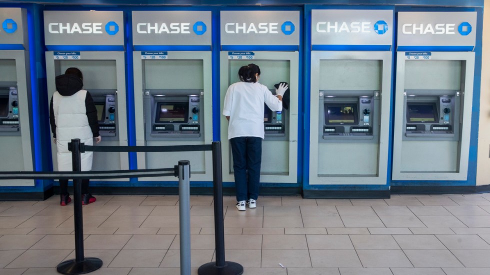En bankanställd desinficerar bankomater i Queens.