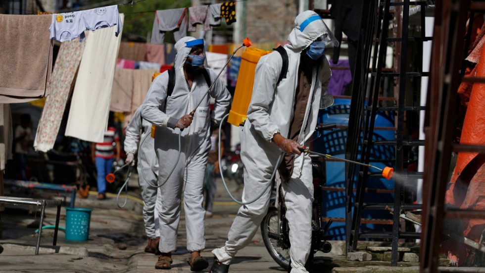 Volontärarbetare sprejar desinfektionsmedel i ett av Islamabads slumområden.