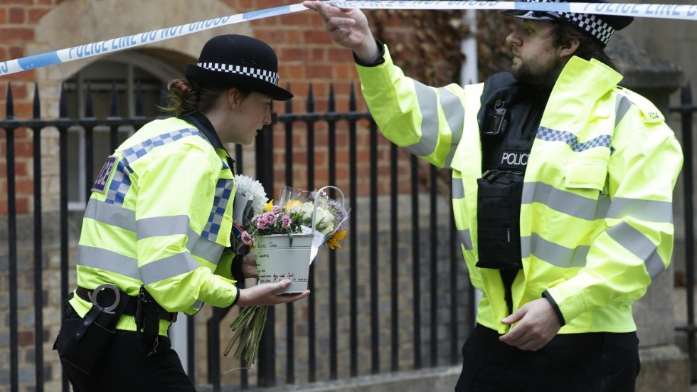 Poliser hämtar blommor som lämnats efter knivdådet i Reading i lördags.