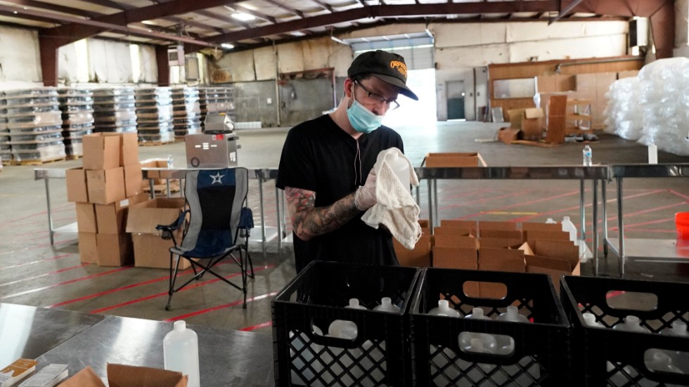 En man torkar av en flaska med handsprit vid en produktionsanläggning i Texas.