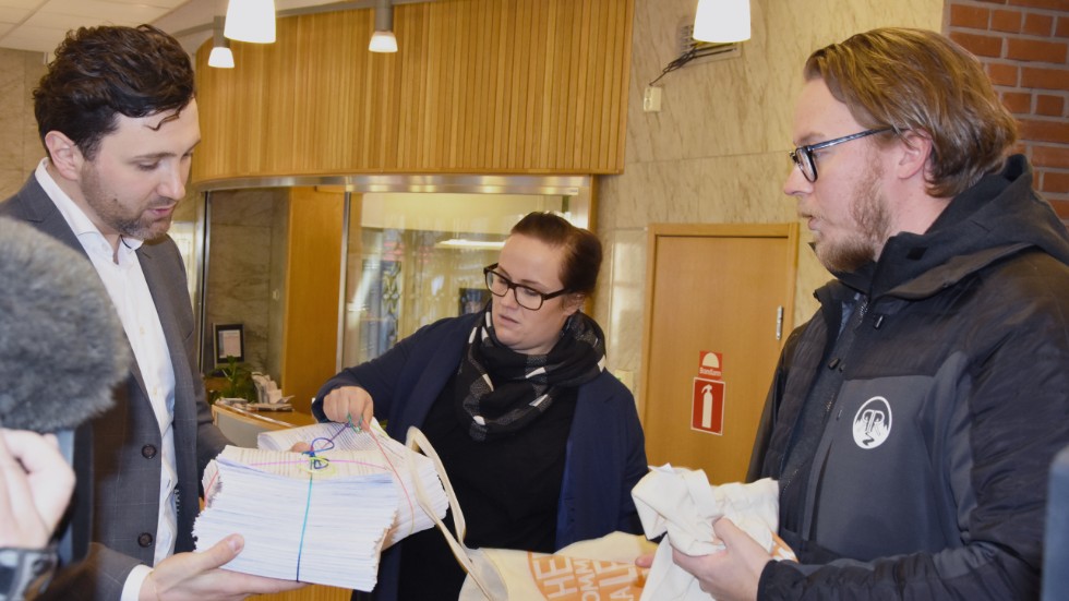 Pontus Johansson från ”Hela kommunen ska leva och lära” lämnar över 9 000 namnunderskrifter till Nihad Zara (M), ordförande i kommunfullmäktiges presidium. 