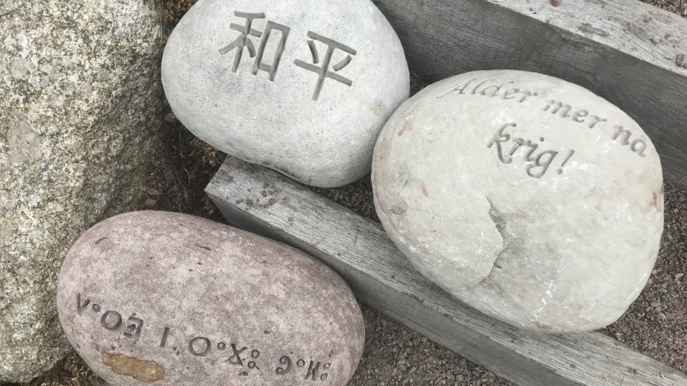 Aldrig mera krig hugget i sten på tre olika spårik. På övre raden i kinesisk skrift samt på Älvdalska. Den nedre på ett skriftspråk som användes av berber i nordafrika.