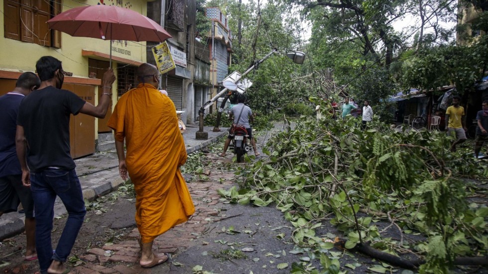 En buddistmunk promenerar längs en väg blockerad av nedfallna träd efter cyklonen Amphans framfart i Calcutta-regionen i Indien. Bilden är från i torsdags.