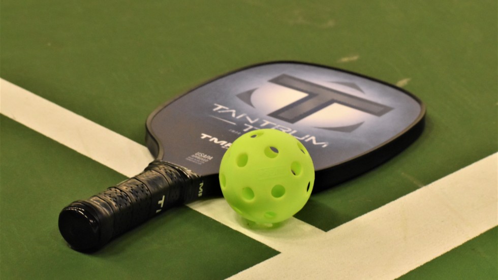 Pickleball spelas med tunna rack och en innebandyboll.
