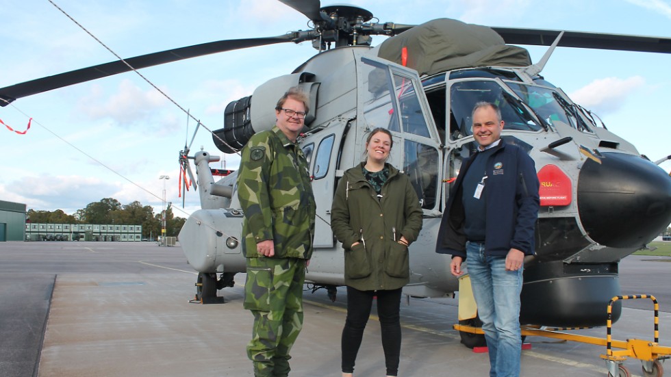 Lasse Jansson, Karolina Hallstedt och Henrik Lilliesköld hälsar allmänheten välkommen till en motordag på Malmen där fokus kommer att vara helikoptrar, som Helikopter 10 i bakgrunden.