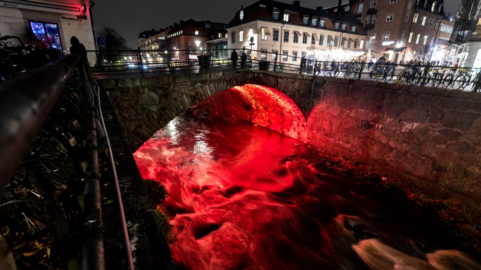 Det skummande vattnet  under Dombron färgas rött av ljusinstallationen ”Glöd över vatten”.