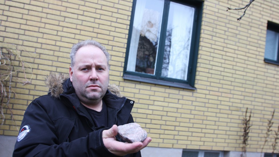 Emil Bruce med den sten som kastades genom en ruta på hans hus i centrala Malmköping. 