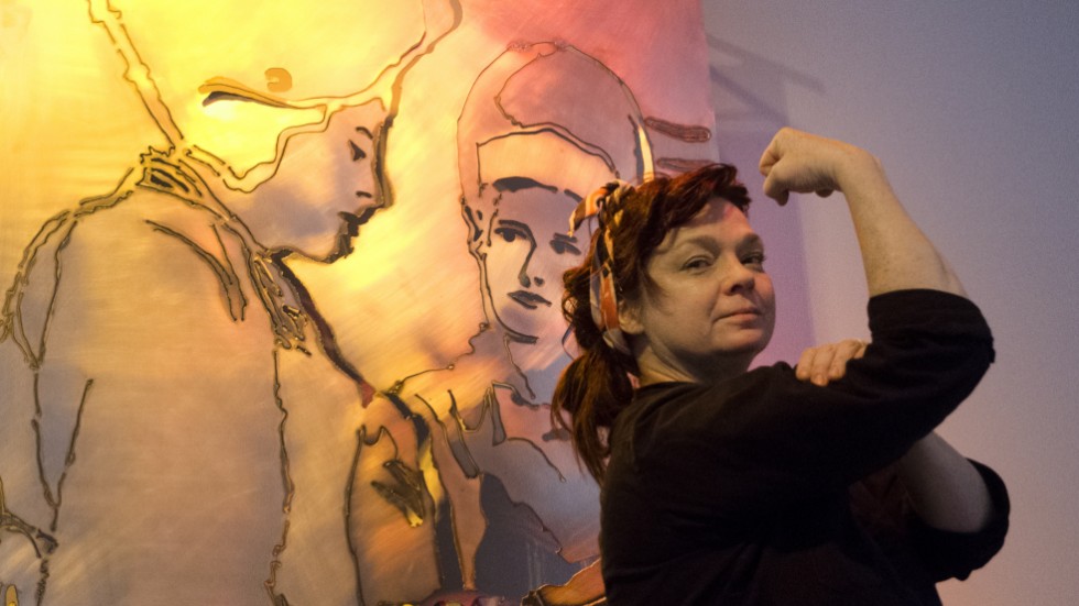 Lokalt förankrade metallkonstnären Jessica Fleetwood är tillbaka i hemstaden med sin nya utställning "Kvinnor i verkstadsindustrin" – en hyllning till kvinnorna i metallindustrin. Bakom henne syns ett av konstverken, skapat i plåt med plasmaskärare.