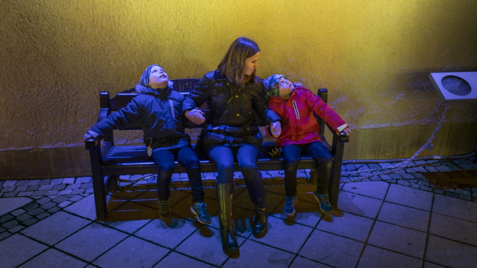 Vid installationen ”Hångelbänken” på Celsiustorget sitter Hannes Brandell, mamma Ida Norlander och Harry Brandell. De får mycket ljus på sig när de håller i varandra.
