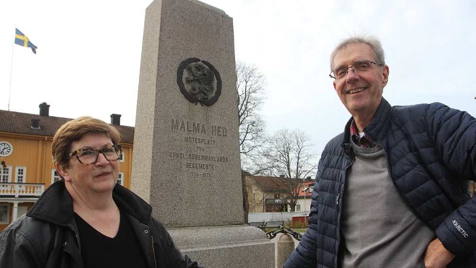 Karin Ögren, utställningsansvarig i Flens kommun, och Göte Johansson, ordförande i Malmköpings hembyggdsförening, framför minnesstenen i Malmköping. 