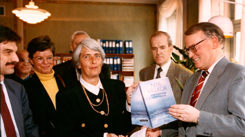 Nionde mars klockan nio på morgonen 1993. Strax före presskonferensen lämnar Assar Lindbeck över kommissionens rapport till dåvarande finansminister Anne Wibble, salig i åminnelse. 