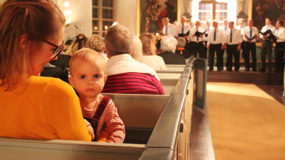 Eva-Karin Dahlberg med barnbarnet Emelinn Larsson, 1 år i famnen. Emelinn tycker att manskören låter lika bra i alla riktningar.