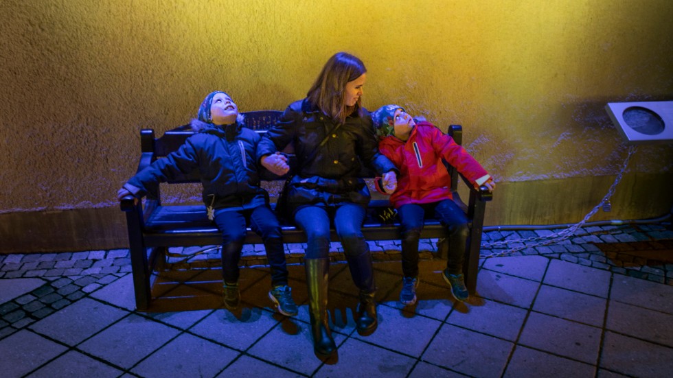 Vid installationen ”Hångelbänken” på Celsiustorget sitter Hannes Brandell, mamma Ida Norlander och Harry Brandell. De får mycket ljus på sig när de håller i varandra.