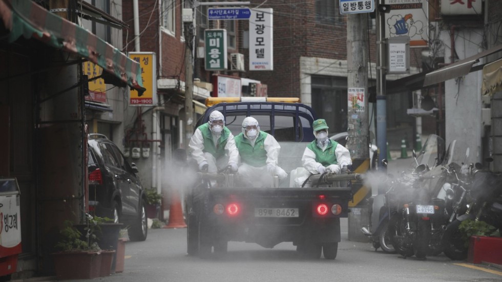 Personer i skyddsmundering sprejar desinficeringsmedel på en gata i Seoul i Sydkorea tidigare i veckan. Metoden får tummen ner av WHO.