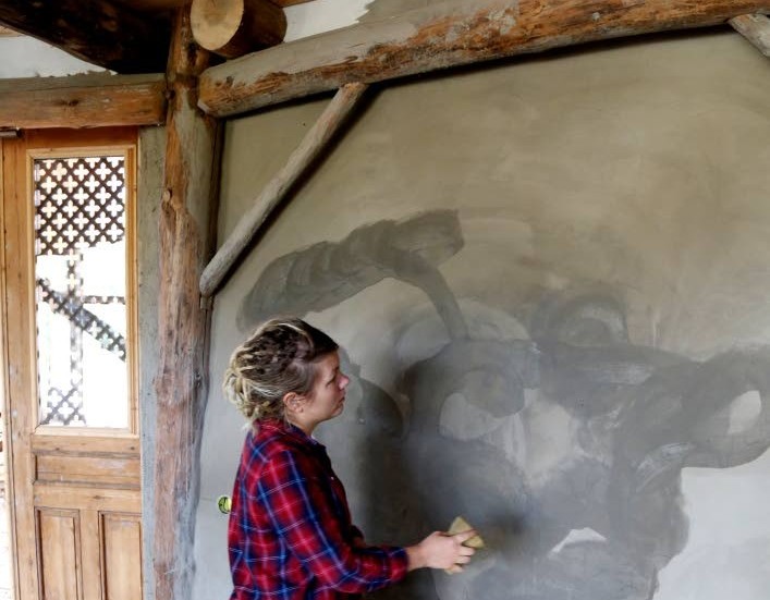 Linnea Salbark är "leransvarig" i bygget. Här lagar hon sprickor som uppstår när leran torkar. Varje vägg består av tre till fem lager lera.
