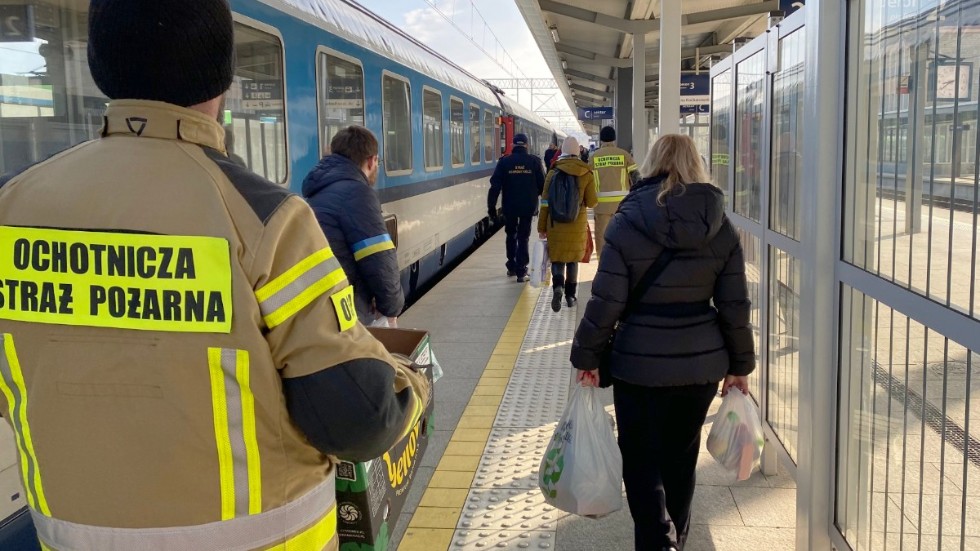 Marcin Grabiec (i jacka med ukrainska flaggan på) och andra volontärer, tillsammans med kommunens anställda, delar ut förnödenheter till flyktingar på tågstationen i polska Rzeszow.