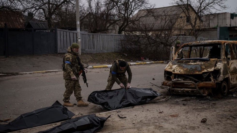 Ukrainska soldater tar om hand kropparna efter fyra dödade civila ur en förkolnad bil i staden Butja utanför Kiev. Bild från den 5 april.