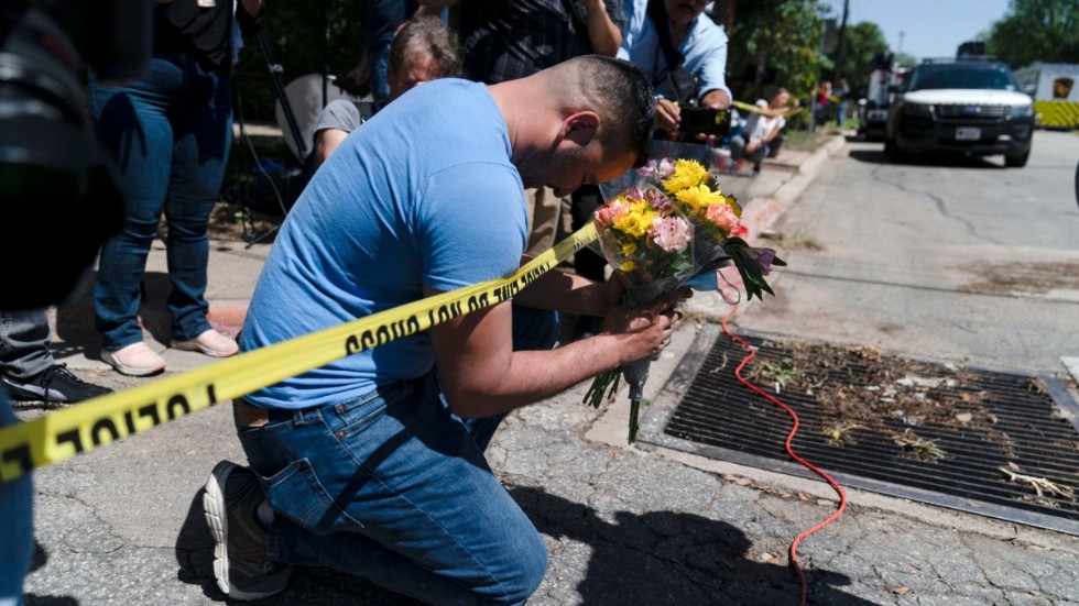En sörjande man håller en bukett blommor vid polisavspärrningarna utanför Robb Elementary School i Uvalde, Texas.