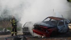Här ser du räddningstjänsten släcka branden i skrotbilarna 