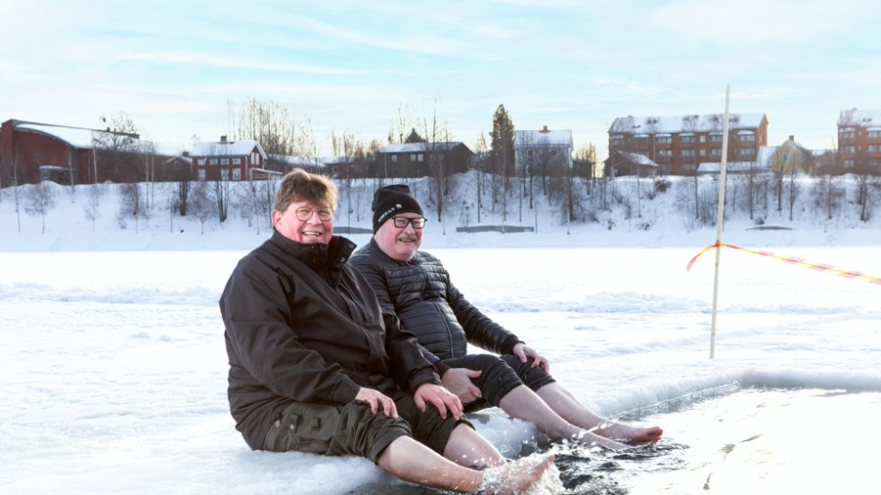 Dark & Cold Winter Swim founders, Jarkko Enqvist (left) and Lasse Westerlund (right) having a paddle in the ice hole on before the Winter Swim event in Skellefteå, 2023.
