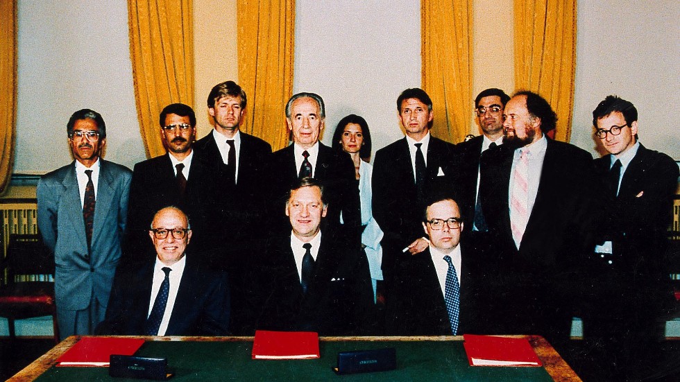 Huvudaktörerna bakom Osloavtalet 1993. I mitten vid bordet sitter Norges dåvarande utrikesminister Johan Jørgen Holst, flankerad till vänster av palestiniernas chefsförhandlare Ahmad Qorei och till höger av israelernas dito Uri Savir. Bakom Holst ses Israels dåvarande utrikesminister Shimon Peres.