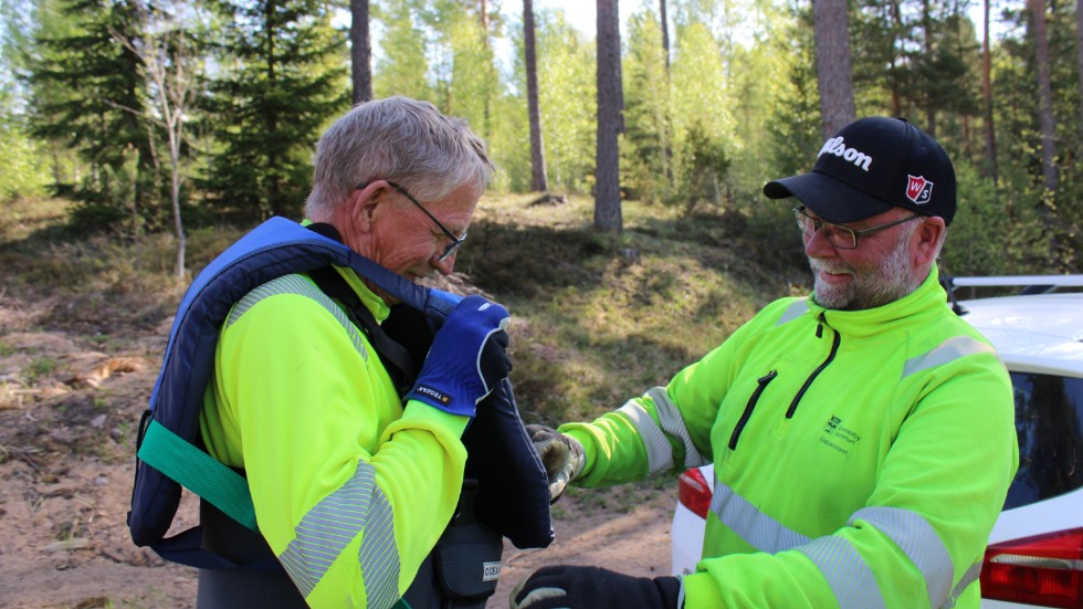 Tony Pettersson, dagens chaufför som körde ut dagens arbetslag för Stångån till Solbacka, hjälper Kenneth Djurstedt med flytvästen.