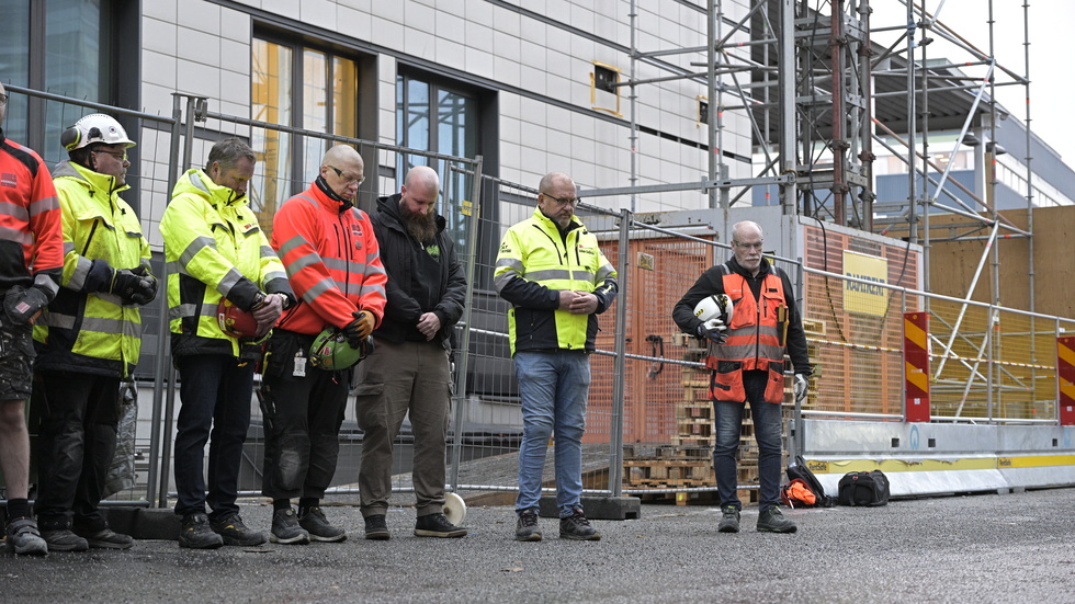 Byggnadsarbetare på en arbetsplats i Solna håller en tyst minut. 