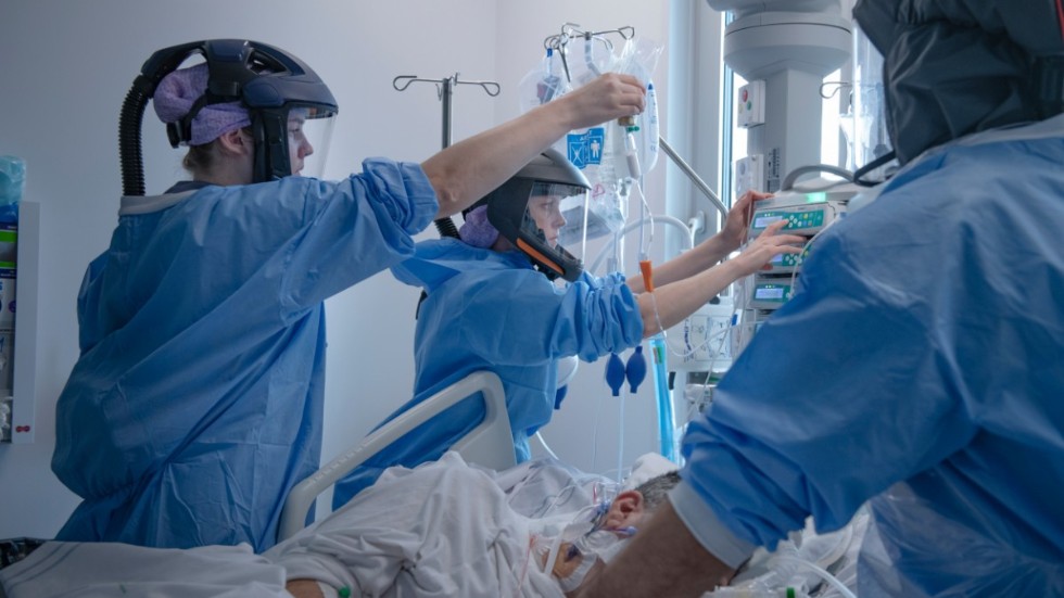 Sjukvårdspersonal i skyddskläder tar hand om en patient på Södertälje sjukhus i april 2020.