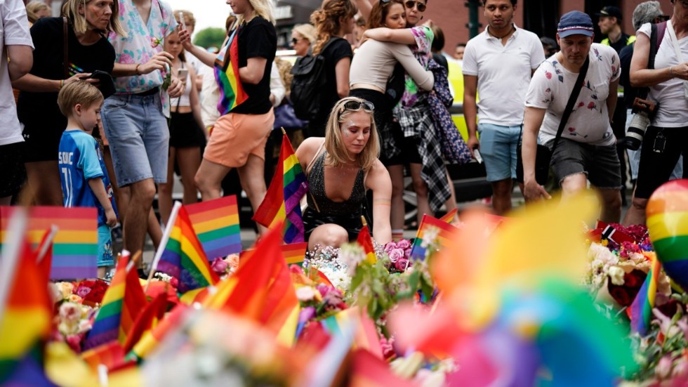 Människor lägger blommor på platsen där två personer dödades och ett 20-tal skadades i en skjutning i Oslo.
