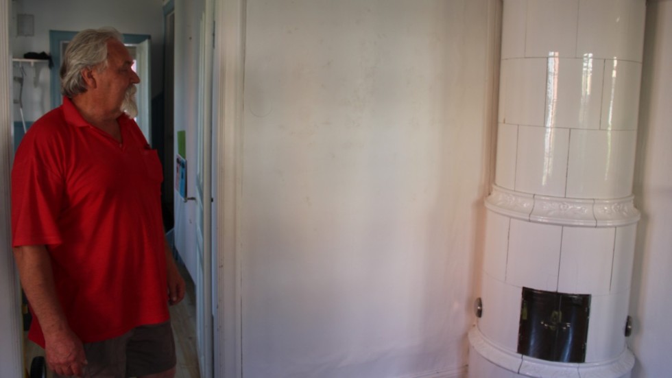 Vesa-Matti Loiske undersöker en vägg och kakelugnen i ett av galleriets andra rum.