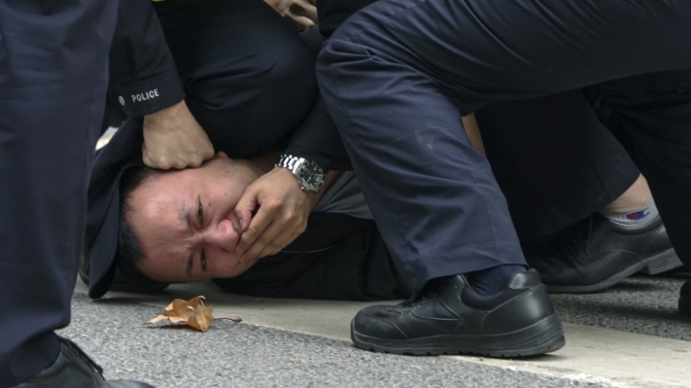 Polisen griper en demonstrant i Shanghai, Kina, under söndagen.