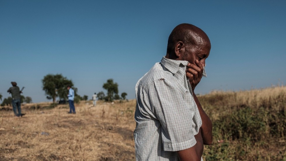 En man står vid ett dike i utkanten av Mai-Kadra i norra Etiopien, där döda kroppar ligger i väntan på att begravas.