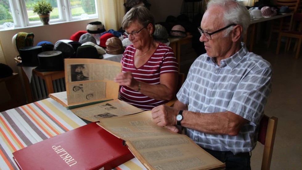 Ingrid och Anders Andersson tittar i gamla pärmar med lokala tidningsurklipp med början av 1950-talet.