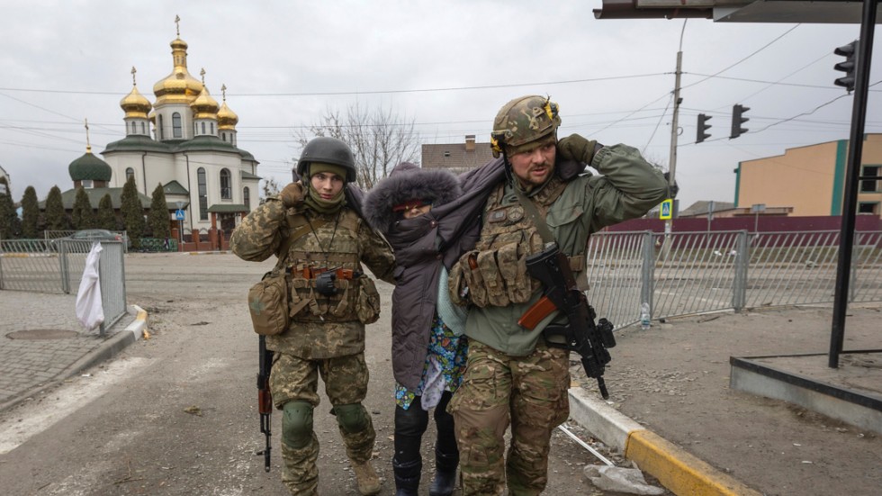 Ukrainska soldater hjälper en kvinna i staden Irpin söndag den 6 mars.