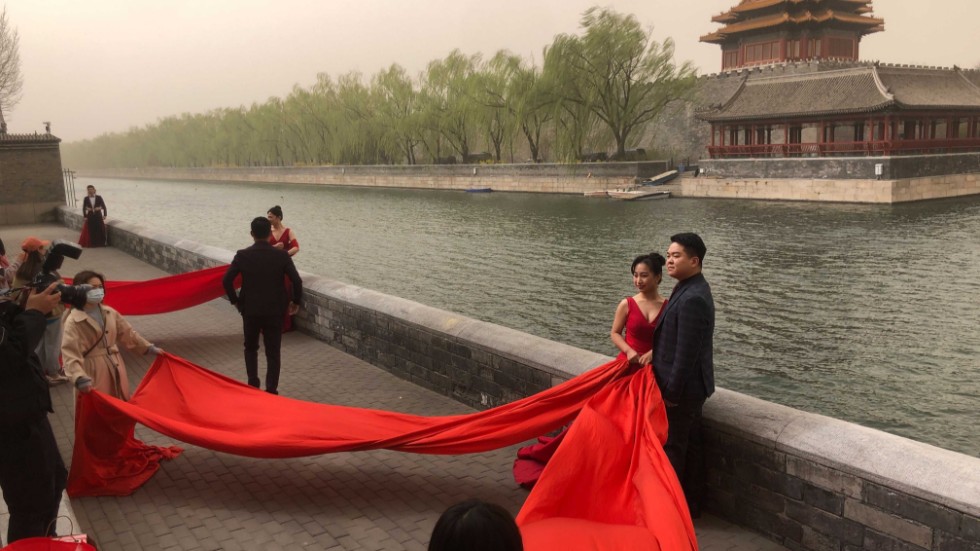 Nygifta par poserar vid Förbjudna staden i Peking. Arkivbild.