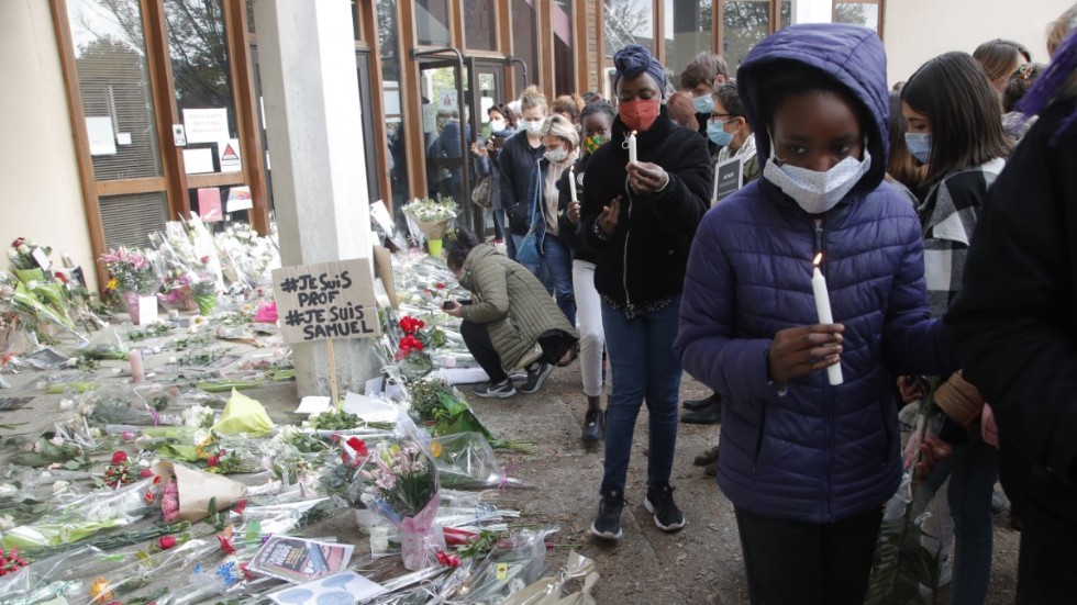 Blommor och tända ljus utanför skolan i Parisförorten Conflans-Sainte-Honorine, där en lärare mördades i fredags.