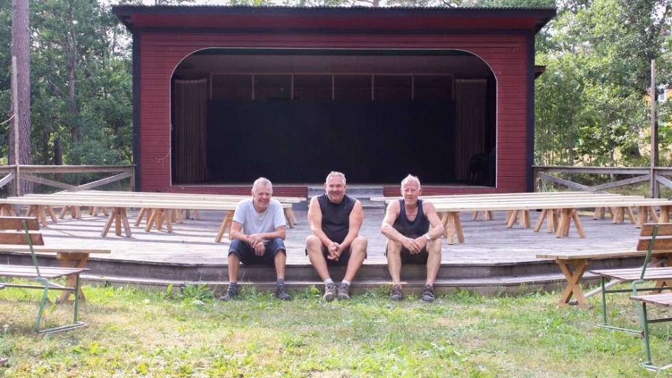 Lennart Nilsson sitter på scenen i hembyggsparken. Tillsammans med Lasse Johansson (till vänster) och Arne Klint (till höger) som har hjälpt till att ställa upp bänkarna.