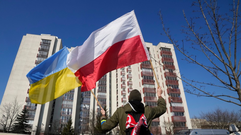 En man håller upp den ukrainska flaggan och den polska flaggan framför en byggnad i P0lens huvudstad Warszawa som hyser ryska diplomater. På fredagen kom beskedet att Ryssland utvisar 45 polska diplomater. Arkivbild.