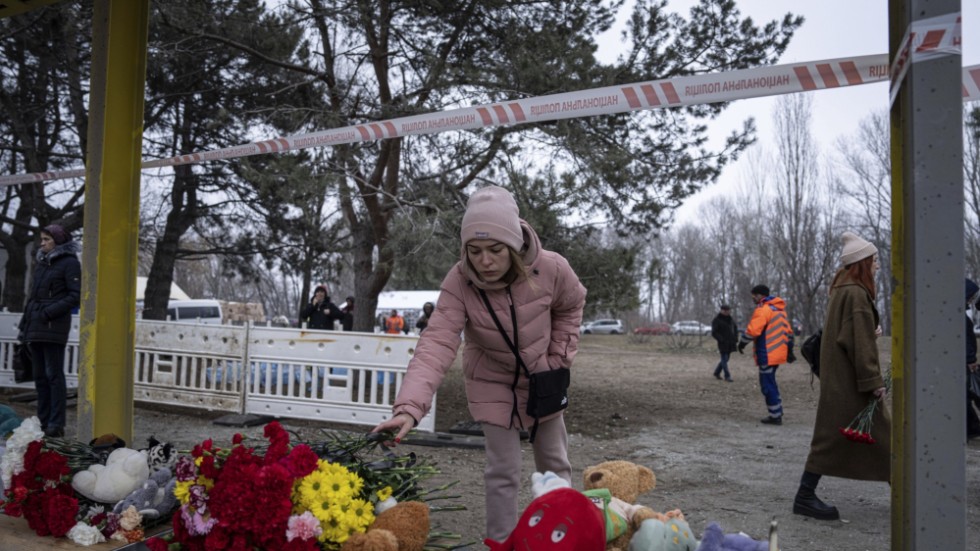 En kvinna lämnar en blombukett vid en busshållplats för att hedra de som dödades i den ryska attacken mot Dnipro.