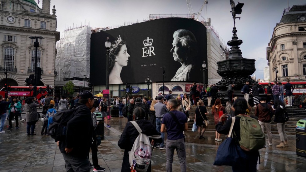 Drottning Elizabeths foto lyser upp en storbildsskärm på ett regnigt Piccadilly Circus i London.