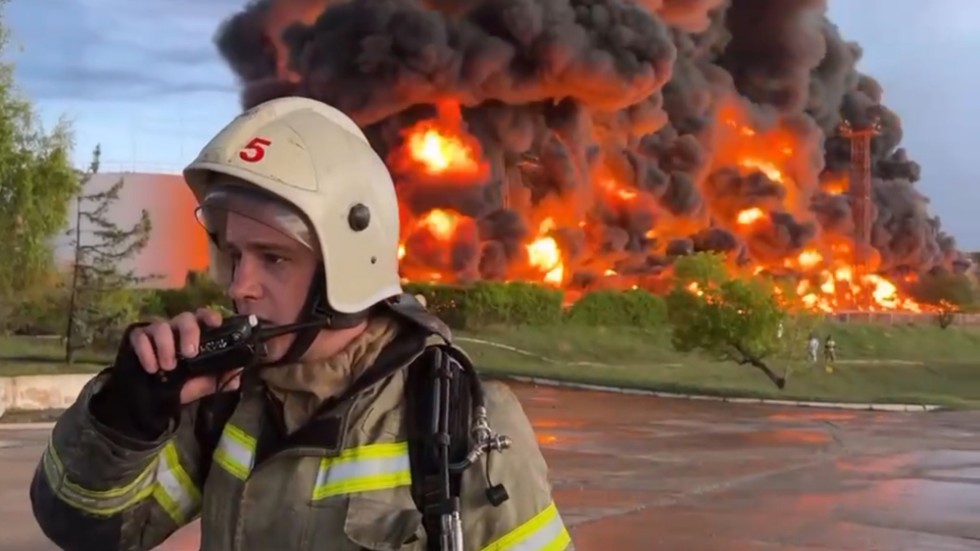 En brandmän pratar i walkie talkie medan lågor slår upp från oljedepån i Sevastopol på Krimhalvön.