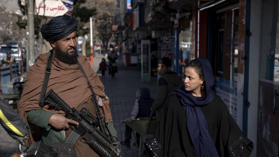 En väpnad taliban patrullerar i Kabul när en kvinna promenerar förbi. Bilden togs den 26 december förra året.