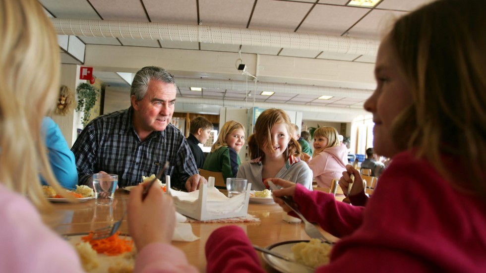 Att äta lunch tillsammans med skolbarnen ska ses som en arbetsuppgift bland andra, och därmed är det orimligt att behöva betala för den, menar debattörerna.