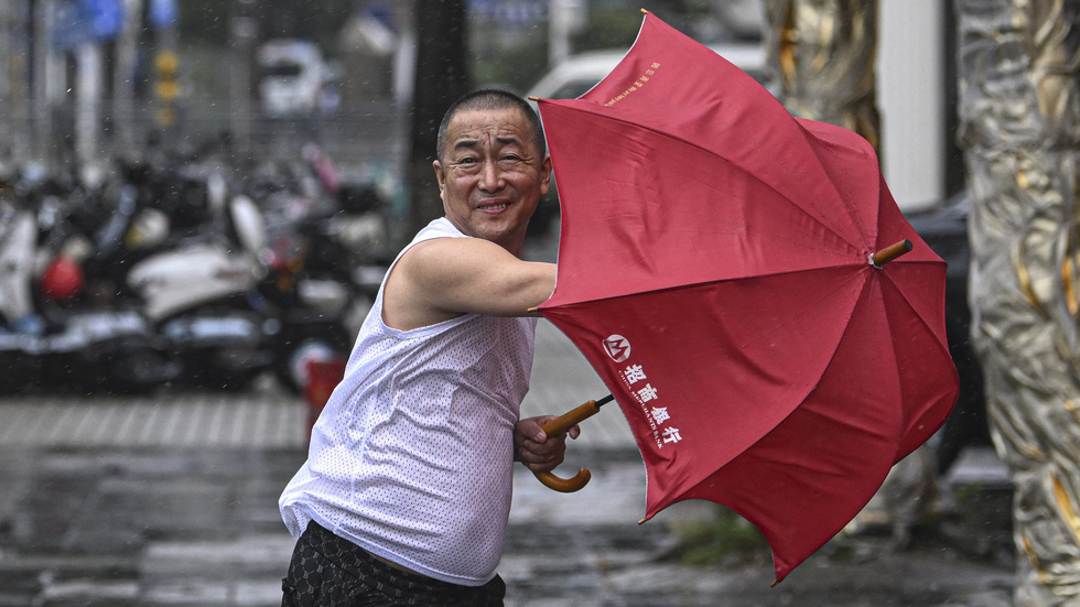 En optimistisk man i Haikou på Hainan gör ett försök att använda paraply trots tyfonen på fredagen.