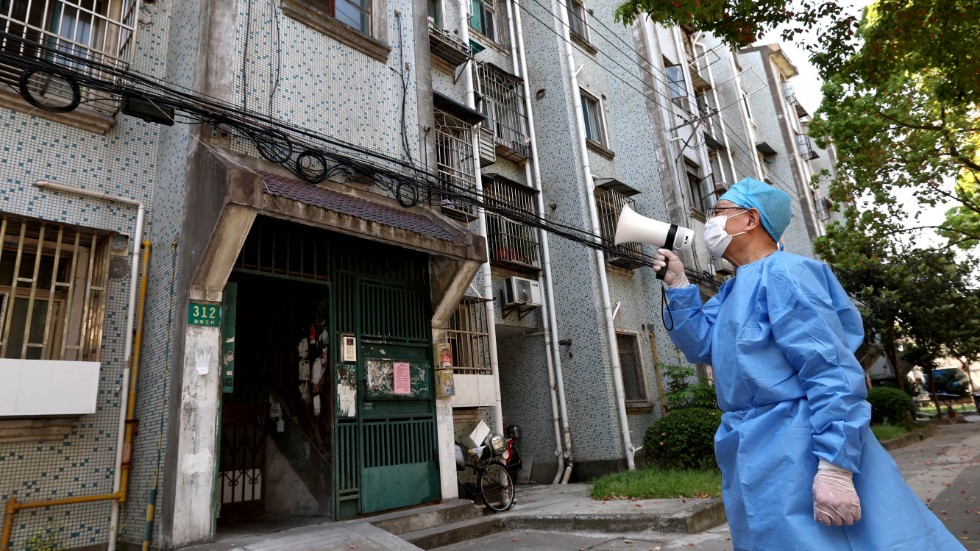 En volontär använder en megafon för att prata med invånare i ett bostadshus i Shanghai.