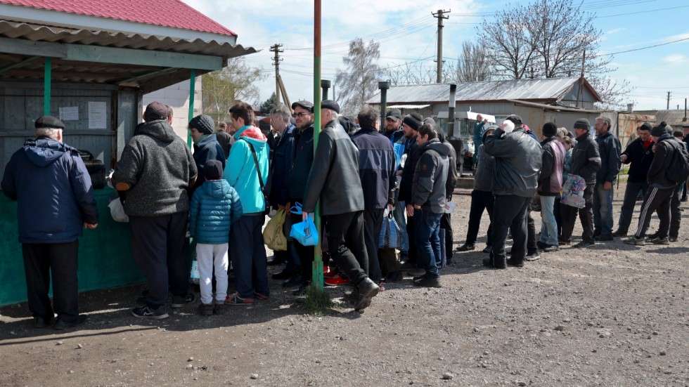 Människor köar för mat i byn Bezimenne i Donetskregionen i östra Ukraina.